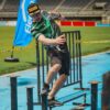 Man participating in an obstacle course race outdoors, balancing on beams.