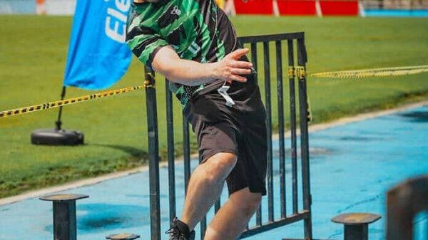 Man participating in an obstacle course race outdoors, balancing on beams.