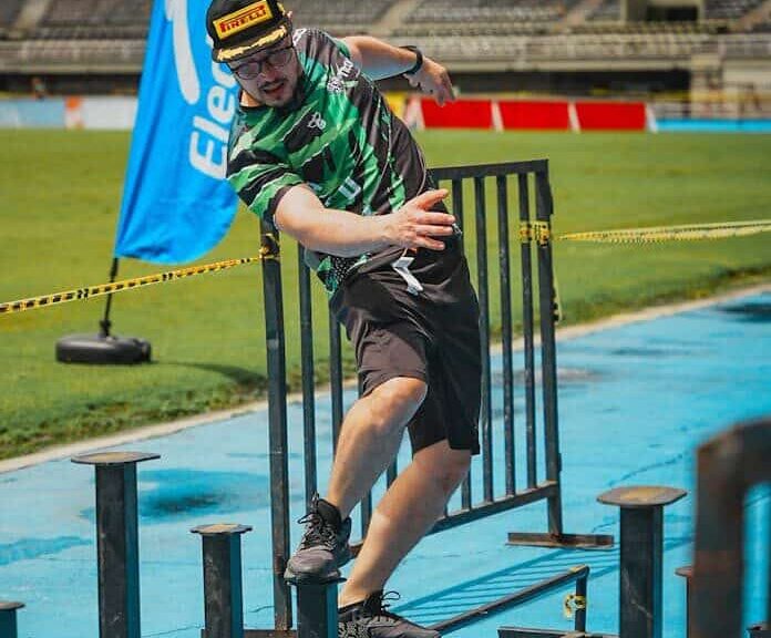 Man participating in an obstacle course race outdoors, balancing on beams.