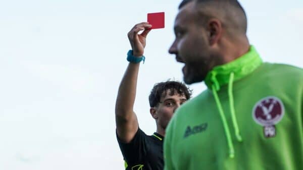 A man in a green hoodie holding up a red card