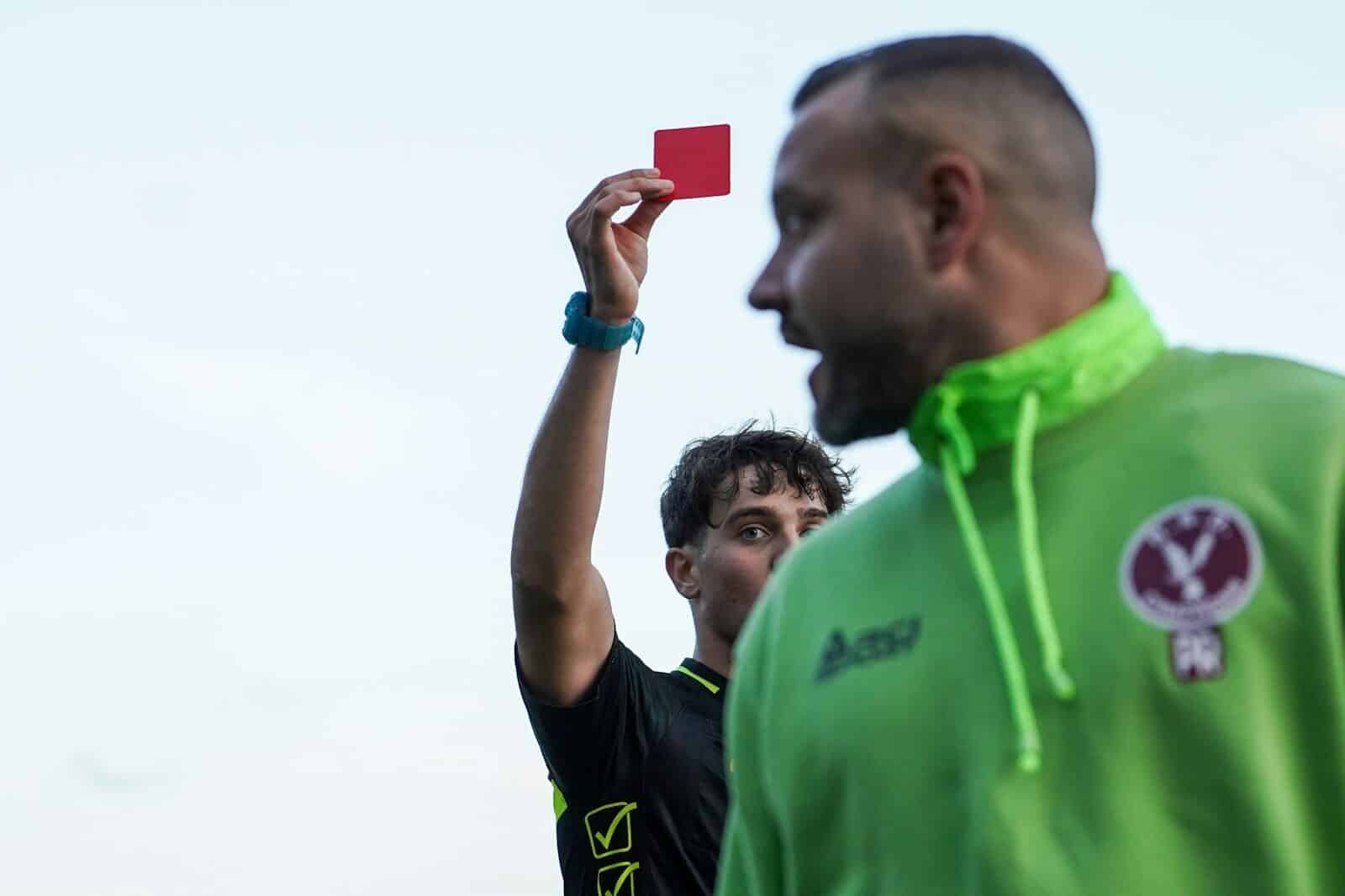 A man in a green hoodie holding up a red card
