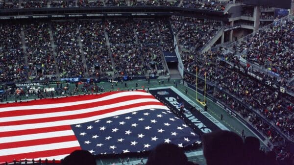 a large american flag is displayed in a stadium