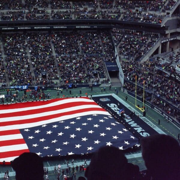 a large american flag is displayed in a stadium