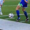 person in blue and white soccer jersey kicking soccer ball on field during daytime