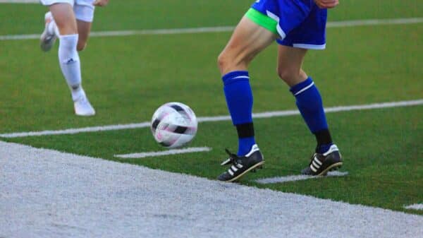 person in blue and white soccer jersey kicking soccer ball on field during daytime