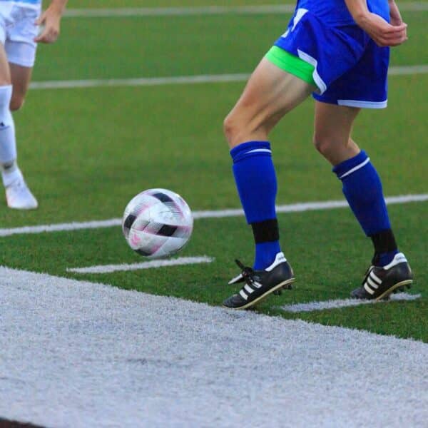 person in blue and white soccer jersey kicking soccer ball on field during daytime
