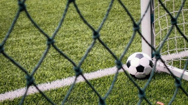 A soccer ball sitting on top of a field next to a goal