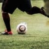 person in black shorts and white nike soccer ball on green grass field during daytime