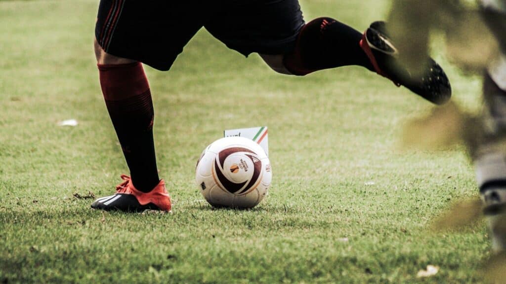 person in black shorts and white nike soccer ball on green grass field during daytime