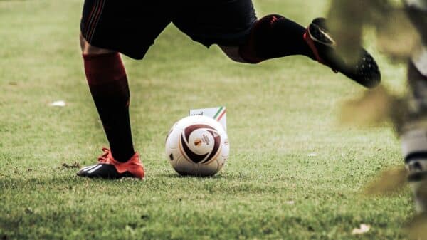 person in black shorts and white nike soccer ball on green grass field during daytime